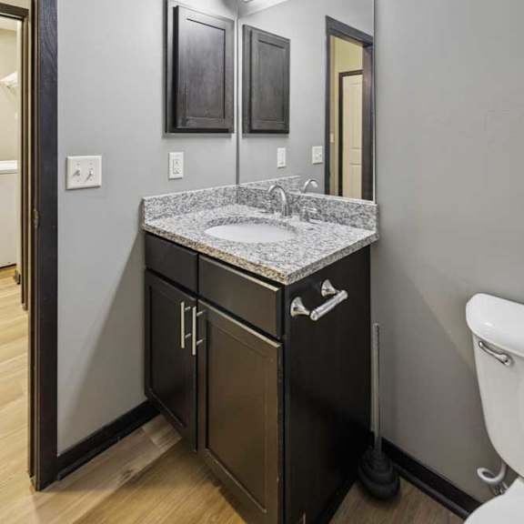 Thumbnail 27 of 33 A bathroom with a granite vanity sink, an oversized mirror with overhead lighting, and a medicine cabinet.