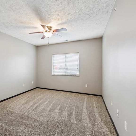 Thumbnail 17 of 33 A carpeted bedroom with a large window and a ceiling fan.