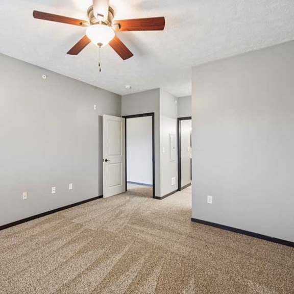 Thumbnail 16 of 33 A carpeted bedroom with a ceiling fan, walk-in closet, and ensuite bathroom.