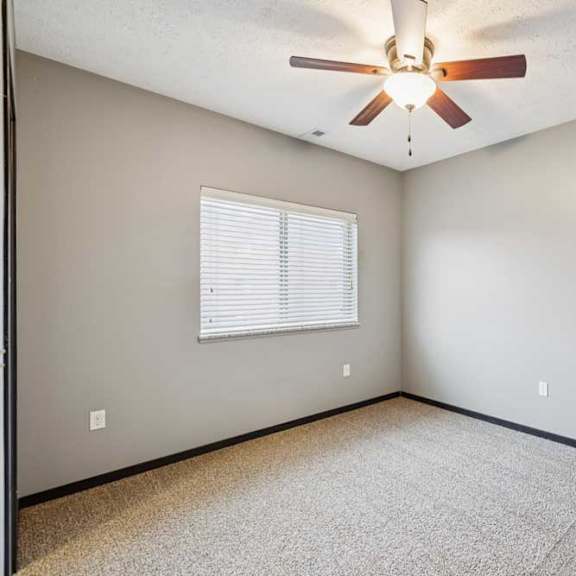 Thumbnail 25 of 33 A carpeted bedroom with a window and a ceiling fan.