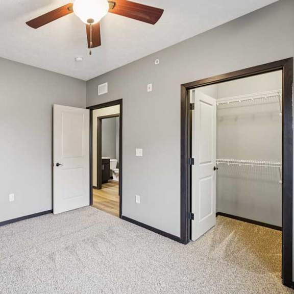 Thumbnail 24 of 33 A carpeted bedroom with a walk-in closet and a ceiling fan.