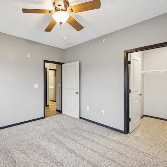 Thumbnail 29 of 33 A carpeted bedroom with a ceiling fan and walk-in closet.