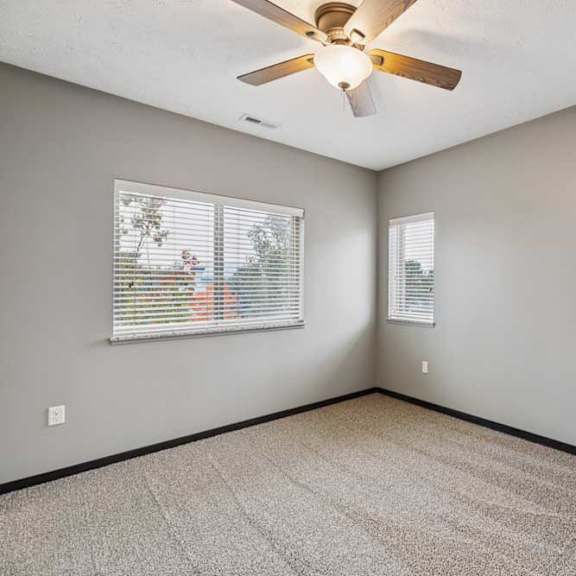 Thumbnail 30 of 33 A carpeted bedroom with several windows, and a ceiling fan.
