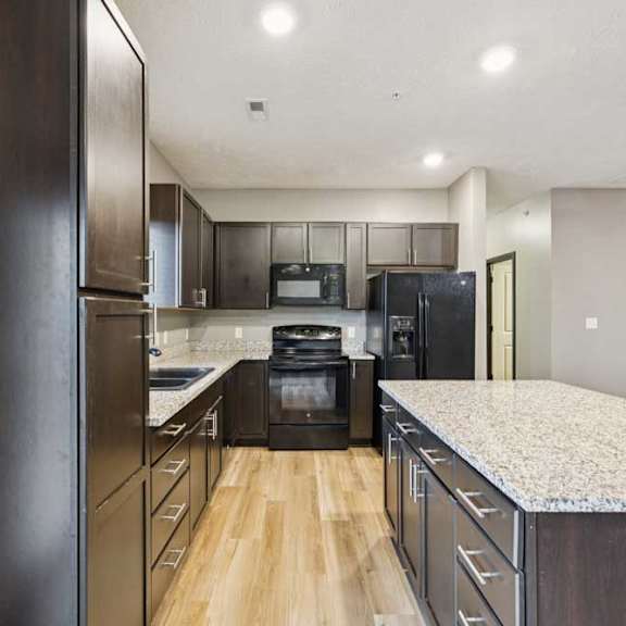 Thumbnail 13 of 33 A kitchen with dark cabinets, granite counters, and black appliances.