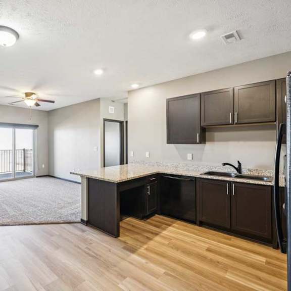 Thumbnail 14 of 30 A modern kitchen with dark brown cabinets and a wooden floor.