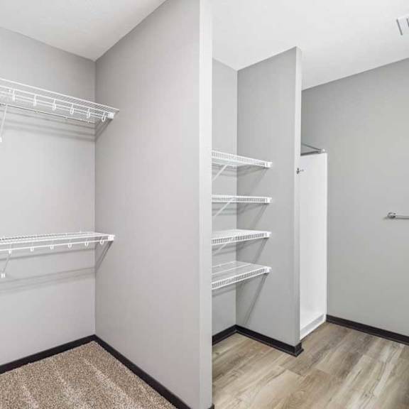 Thumbnail 26 of 30 A white walk-in closet with shelves and an open door.