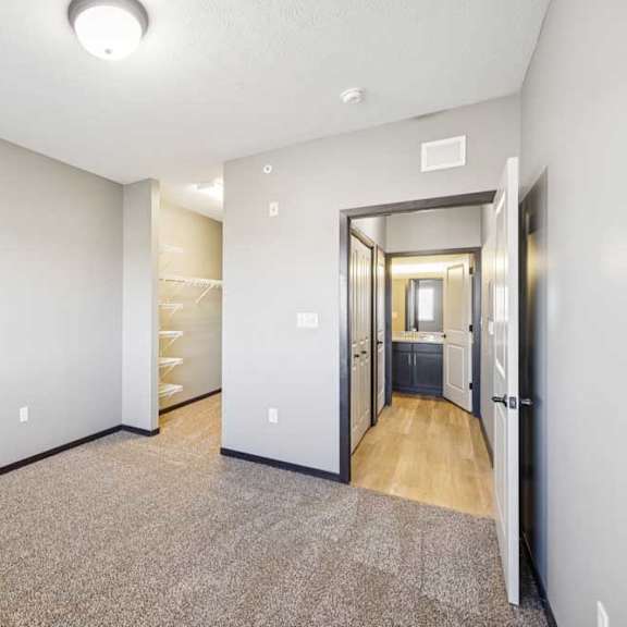 Thumbnail 29 of 30 Bedroom with carpet and ceiling light, featuring an open closet and direct access to a bathroom with wood-style flooring.