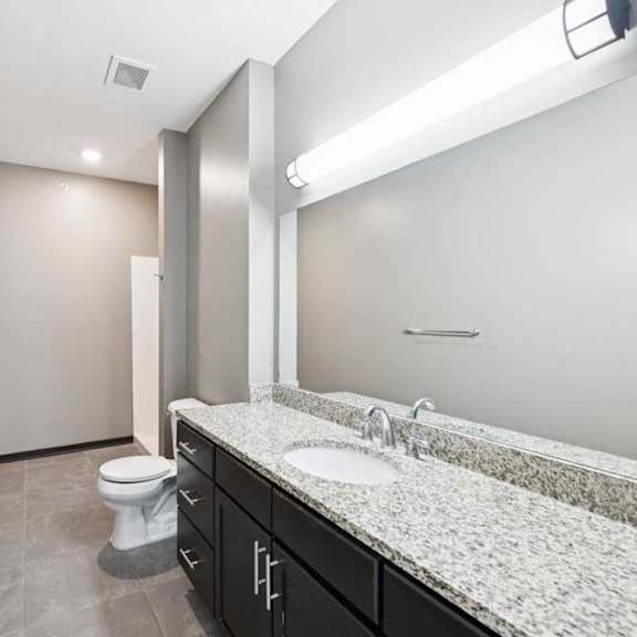 Thumbnail 18 of 23 A bathroom with a toilet, sink, and mirror.