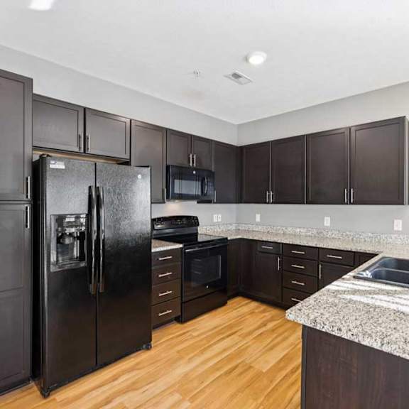 Thumbnail 4 of 23 A kitchen with a black refrigerator, microwave, and oven.