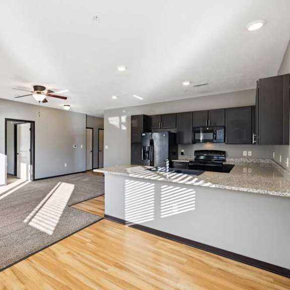 Thumbnail 7 of 23 A modern kitchen with a wooden floor and a ceiling fan.