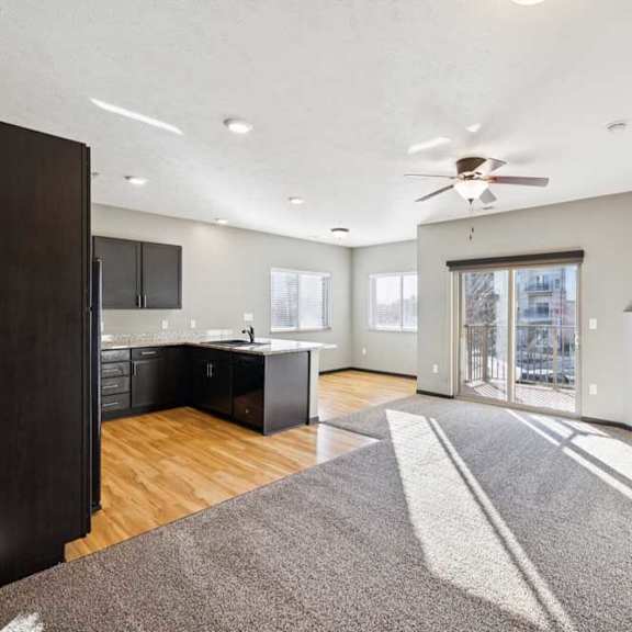 Thumbnail 3 of 23 A modern kitchen with a dark wood floor and a ceiling fan.