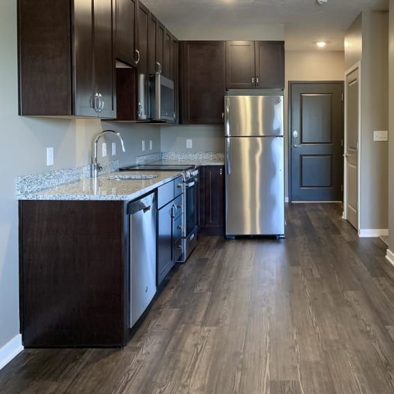 Thumbnail 7 of 16 Kitchen with dark brown cabinets and matching stainless steel appliances in a studio apartment at the flats at shadow creek