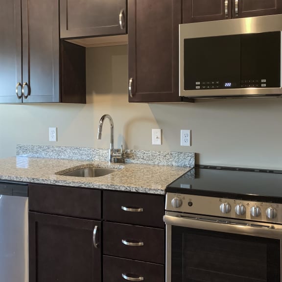 Thumbnail 3 of 16 Kitchen with dark brown cabinets and matching stainless steel appliances in a studio apartment at the flats at shadow creek