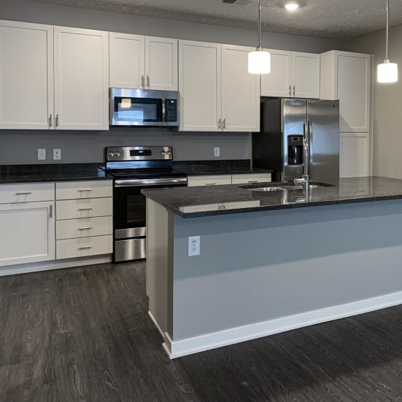 Thumbnail 2 of 20 Spacious kitchen with white cabinets and large floating island with granite countertops