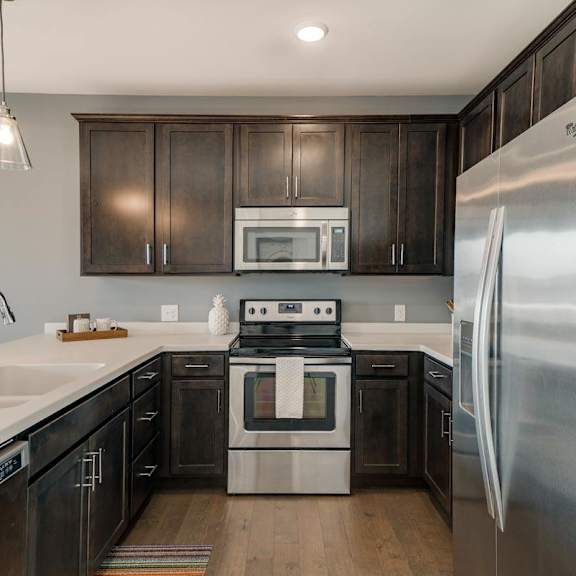 Thumbnail 3 of 16 A modern kitchen with dark wood cabinets and stainless steel appliances.