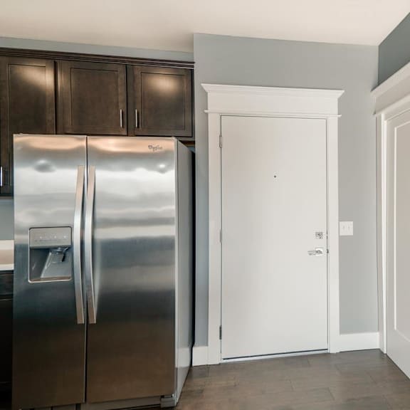 Thumbnail 11 of 16 A kitchen with a refrigerator, a door to hallway and closet with stacked washer and dryer.