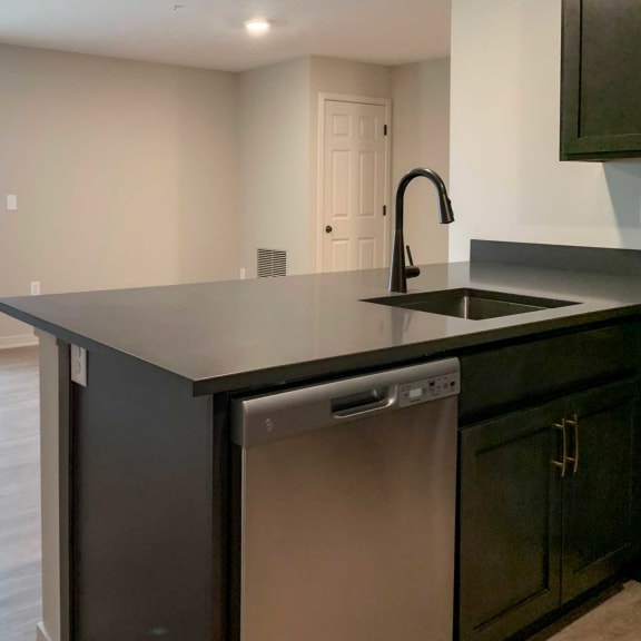 Thumbnail 6 of 20 a kitchen with stainless steel dishwasher next to the sink and dark wood cabinets