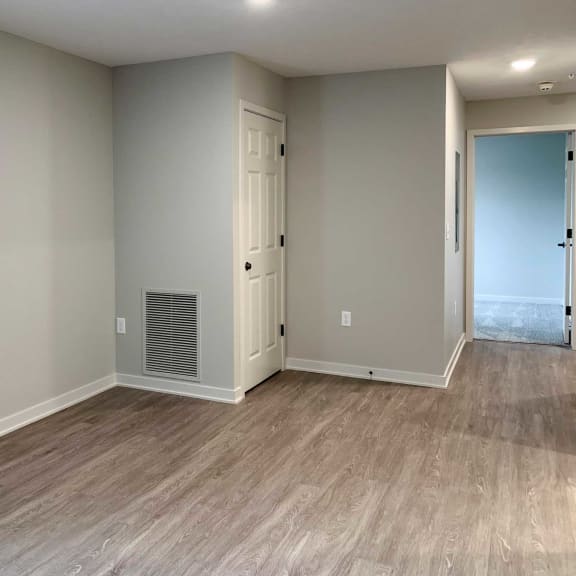 Thumbnail 17 of 20 a living room with a door to a hallway and wooden flooring