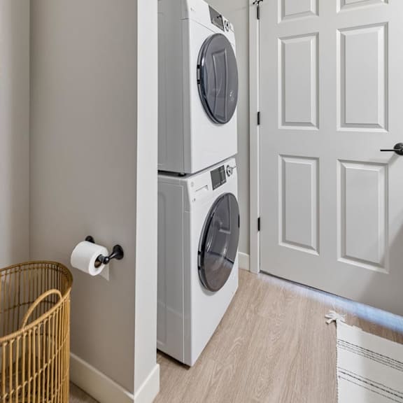 Thumbnail 38 of 39 Apartment laundry area with stacked washer and dryer beside paneled doors.