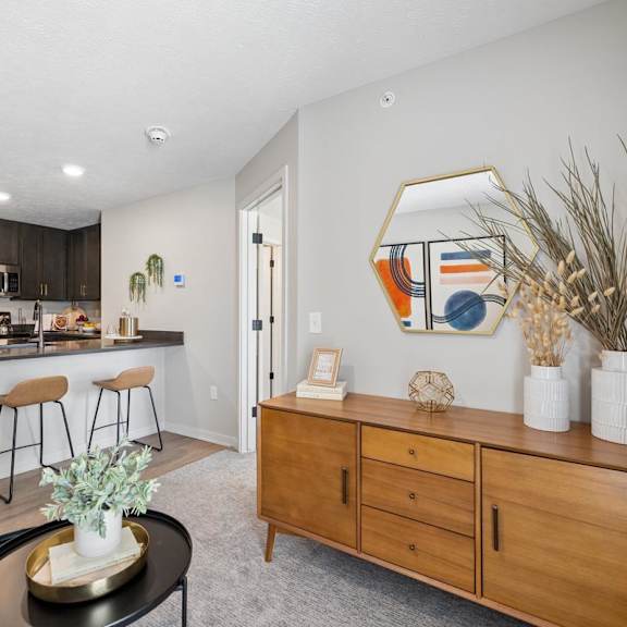 Thumbnail 31 of 39 Open-concept apartment living area with a kitchen island, bar seating, stainless steel appliances, and modern furnishings.