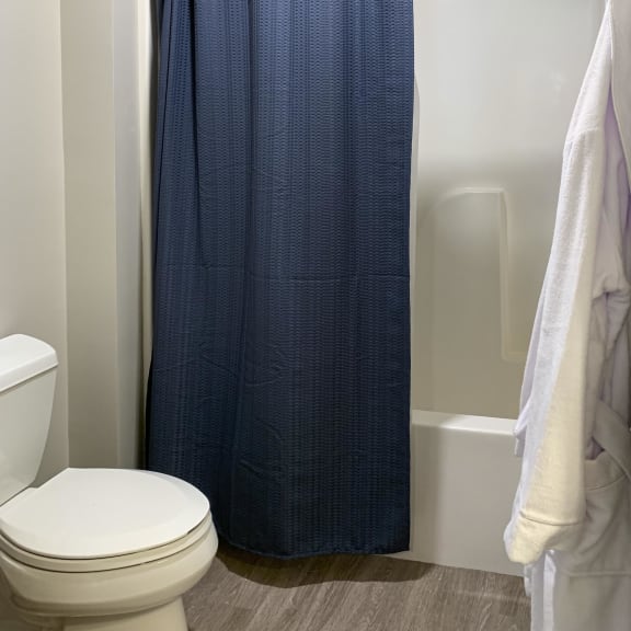Thumbnail 15 of 24 a small bathroom with a white toilet and a blue shower curtain