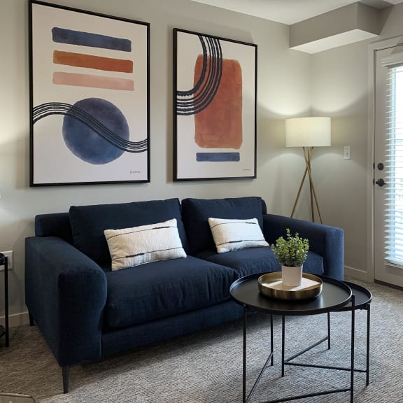 Thumbnail 12 of 24 a living room with a blue couch and two paintings on the wall