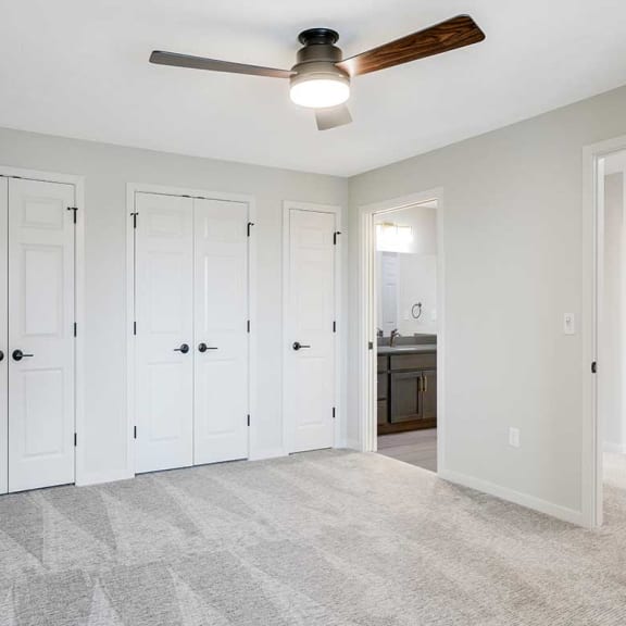 Thumbnail 24 of 29 a bedroom with 3 closets, a ceiling fan, and a door to the attached bath