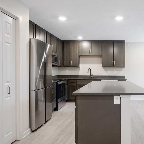 Thumbnail 10 of 29 a kitchen with dark cabinets, an island, and stainless steel appliances