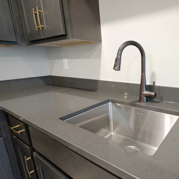 Thumbnail 12 of 29 a kitchen drop-in sink with a gooseneck faucet in a stone countertop