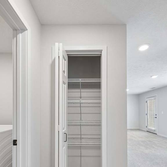 Thumbnail 32 of 36 Apartment hallway with linen closet, built-in wire shelving, and neutral carpeting.