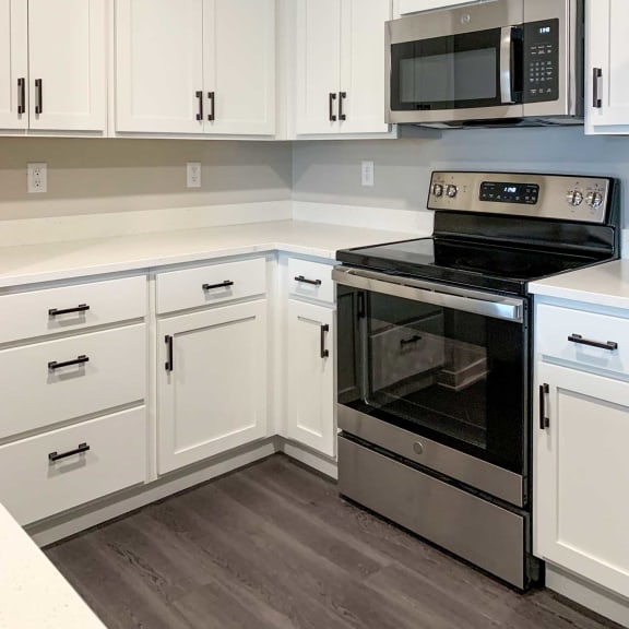 Thumbnail 18 of 24 a kitchen with white cabinets and countertops and stainless steel oven and microwave