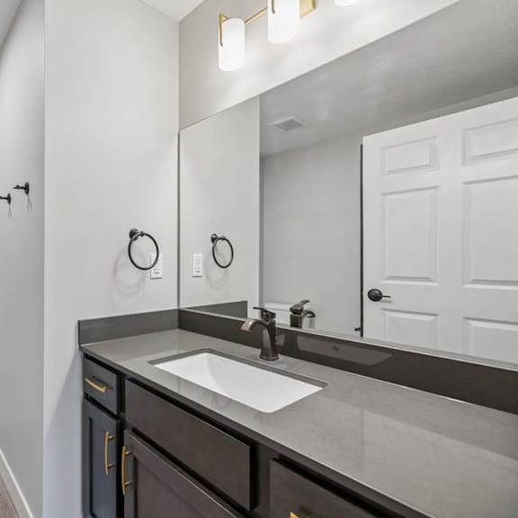 Thumbnail 40 of 52 Apartment bathroom with a single-sink vanity, dark cabinetry, a large framed mirror, and a tub-shower combination with a white surround.