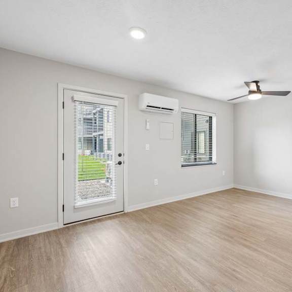 Thumbnail 38 of 52 Bright apartment living room with wood-style flooring, recessed lighting, a glass patio door, ceiling fan, and an open closet near the entry.
