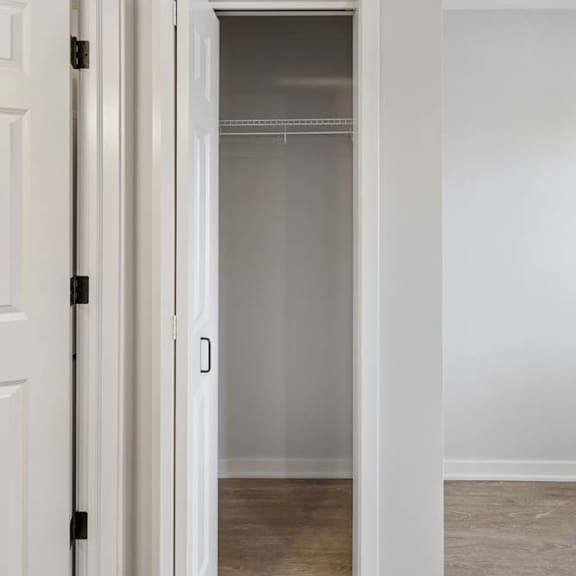 Thumbnail 51 of 52 Apartment closet with built-in shelving and a hanging rod, featuring a white bifold door, neutral walls, and wood-style flooring.
