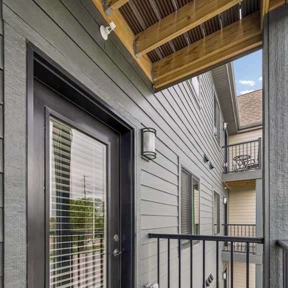 Thumbnail 33 of 52 Apartment balcony with glass patio door, privacy railing, and covered outdoor space.