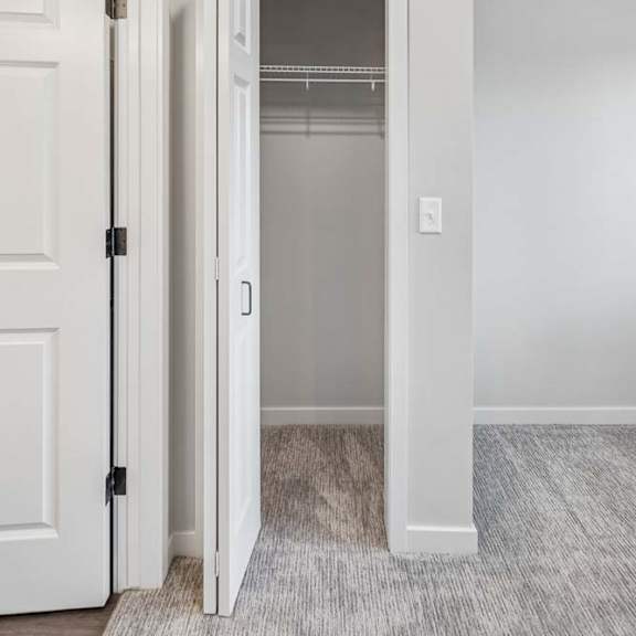 Thumbnail 32 of 52 Apartment hallway with linen closet, built-in shelving, and neutral carpeting throughout.
