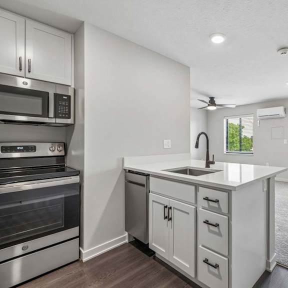 Thumbnail 26 of 52 Open apartment living area with kitchen island, stainless steel appliances, and private balcony access.