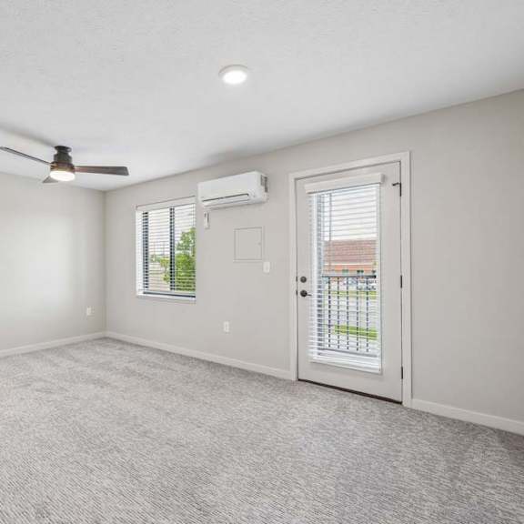 Thumbnail 30 of 52 Apartment living area with ceiling fan, large window, and glass door leading to a private balcony.
