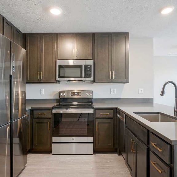 Thumbnail 4 of 19 A kitchen with stainless steel appliances and dark cabinets