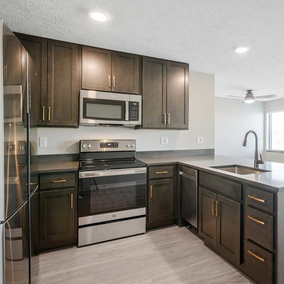Thumbnail 6 of 19 A kitchen with stainless steel appliances and dark cabinets