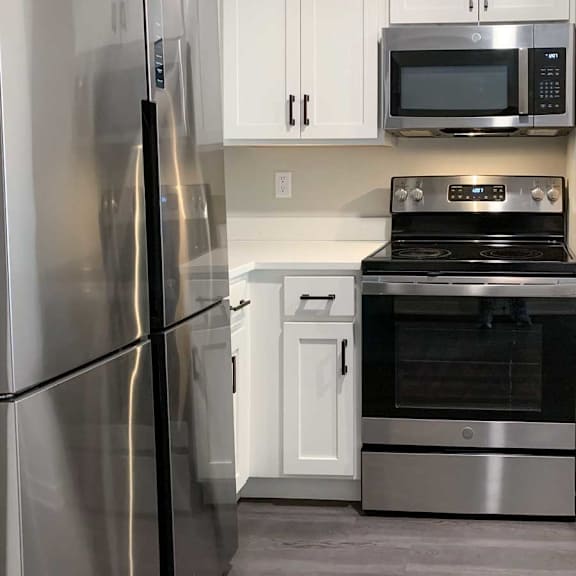 Thumbnail 18 of 25 a kitchen with white cabinets, light quartz countertops, and stainless steel appliances