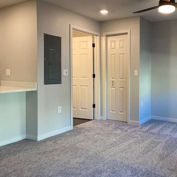 Thumbnail 23 of 25 a living area with a closet, a ceiling fan, and a door to the bathroom