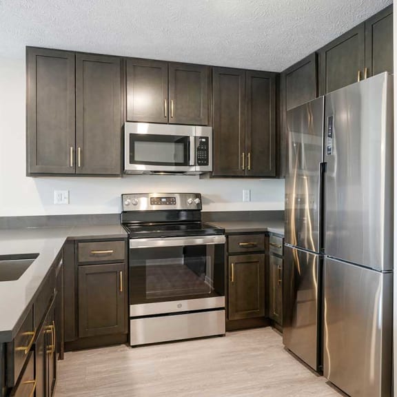 Thumbnail 4 of 17 a kitchen with stainless steel appliances and dark wooden cabinets