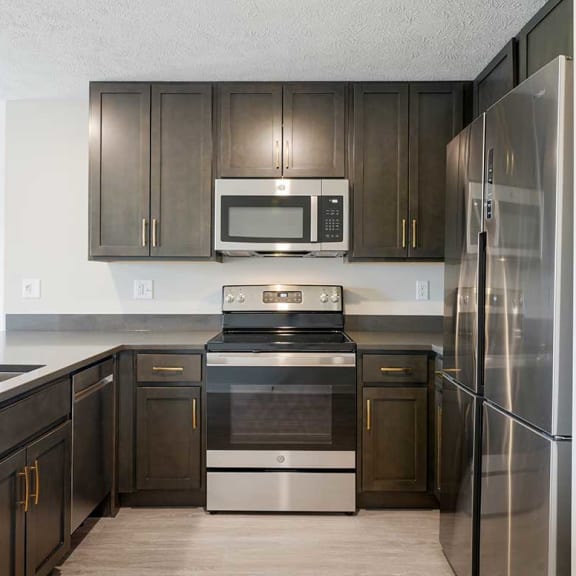 Thumbnail 3 of 17 a kitchen with stainless steel appliances and dark wooden cabinets