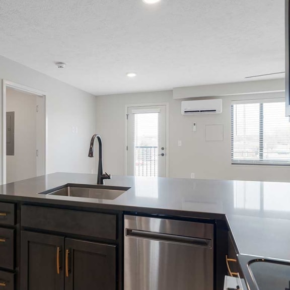 Thumbnail 6 of 17 a kitchen with a sink and a counter top and dark cabinets