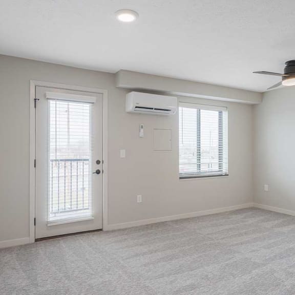 Thumbnail 9 of 17 the main room with a ceiling fan, wall-mounted A/C, large window, and door to balcony