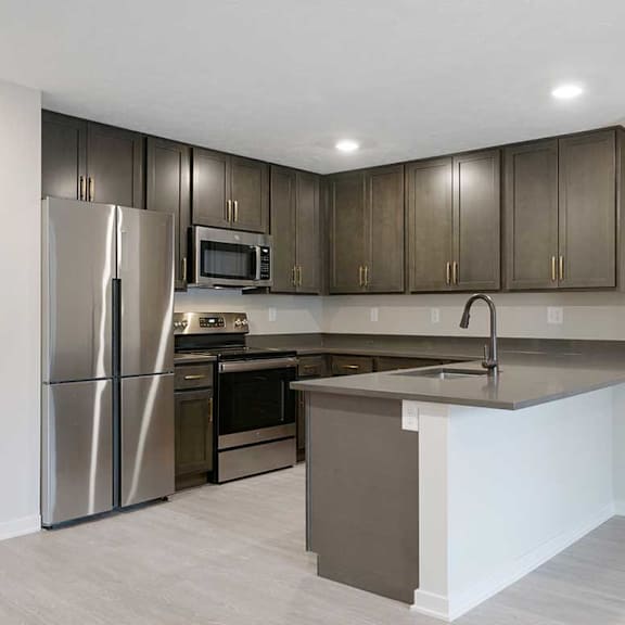 Thumbnail 8 of 30 A U-shaped kitchen with dark cabinets and stainless steel appliances