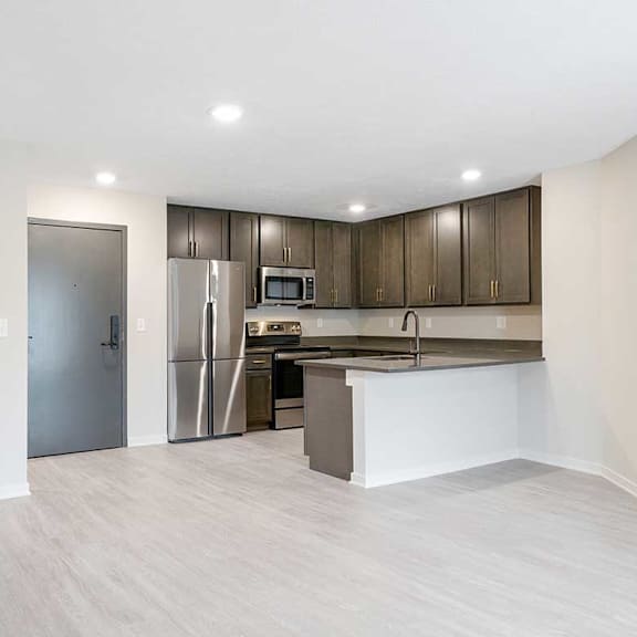 Thumbnail 9 of 30 A wide view of the kitchen featuring dark cabinets, stainless steel appliances, and a peninsula countertop