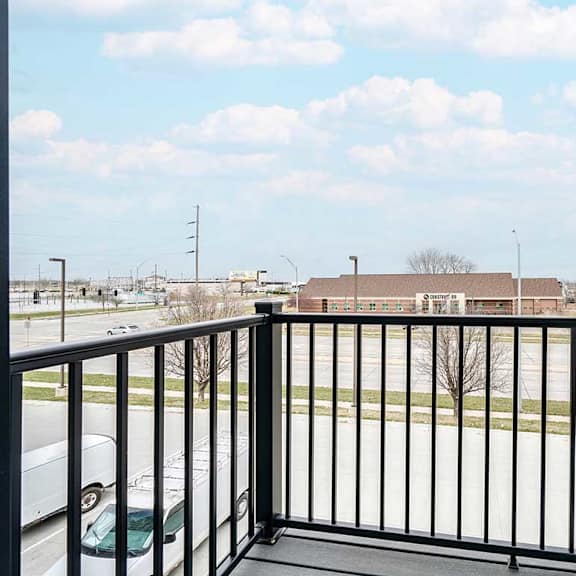 Thumbnail 11 of 25 a balcony with a view of a parking lot and a building