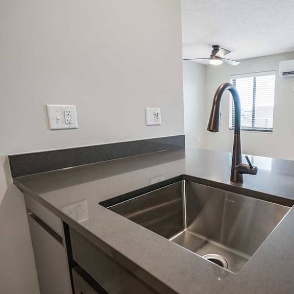 Thumbnail 5 of 25 a drop-in kitchen sink with a gooseneck faucet in a stone countertop